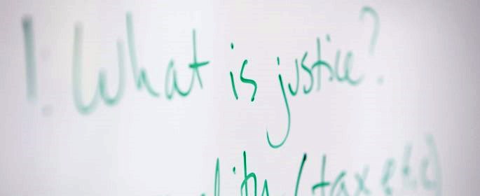 Image shows a whiteboard with "What is justice?" written on it.