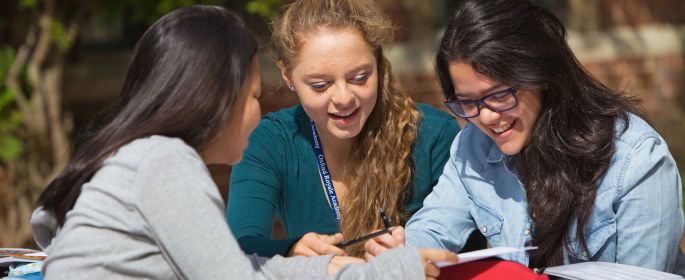 Image shows three students working outside.