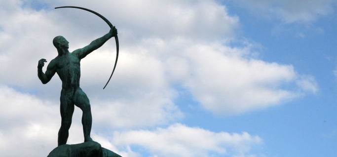 Image shows a statue of an archer against a blue sky.